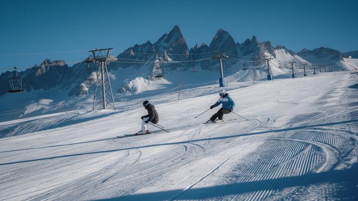 Skiers on a groomed piste below the peaks above St. Anton am Arlberg